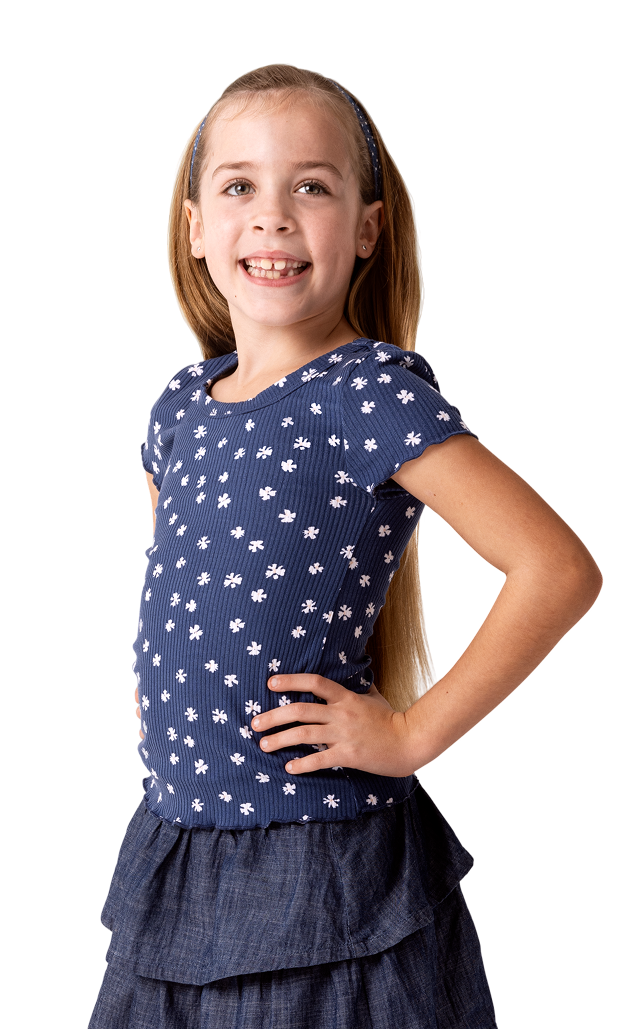Cora, a child living with XLH, standing and smiling with her hand on her hip