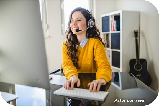 A woman smiling at her desk with a headset on
