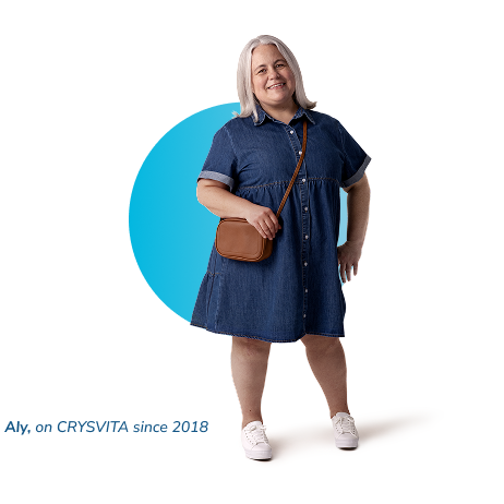 Aly, a person living with XLH, standing and smiling while holding her purse